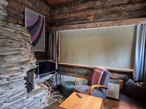 Living room with a natural stone fireplace, a television and comfortable armchairs.