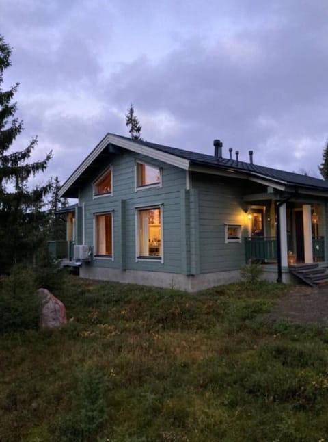 Log-built exterior of the apartment with warmly lit windows in the evening.