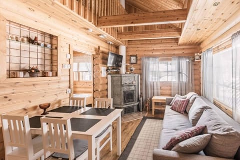 Bright open-plan living room and kitchen area with a wood-burning fireplace, a dining table, and a comfortable sofa.