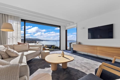 Sink into the generous lounge as floor-to-ceiling glazing frames an uninterrupted sweep across the River Derwent, transforming every quiet moment into a front-row coastal experience.