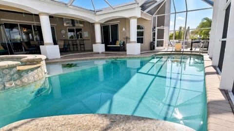 South-facing screened pool area at Villa Almare with heated saltwater pool, spa, and spacious covered terrace.