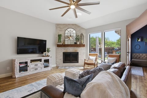 Open Living Room featuring a 65-inch Smart TV, wood-burning Fireplace with fire screen, and large sliding doors letting in lots of natural light.
