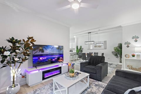 Open-concept living room with a cozy couch, chair, 75" TV, and fireplace. High-speed internet and a patio door leading outside make this a comfortable spot to relax after a day of exploring.