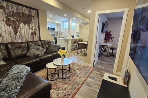 The living room features a comfortable sofa, a stylish coffee table, and an entertainment center with a 65" TV offering Netflix, Prime Video, YouTube, numerous channels, and more.