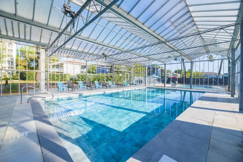 Slip into the indoor pool beneath the glass-paneled roof, with loungers lined up along the tiled deck.