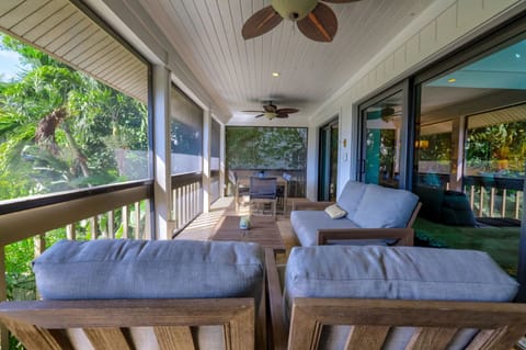 Sunlight streams through the screens, illuminating the cozy seating on the private porch surrounded by lush greenery.