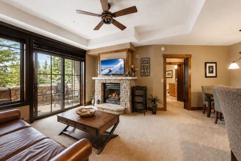 Relax in your spacious living room where mountain air flows through balcony doors and warm firelight dances on stone, creating the perfect alpine retreat for cozy evenings.