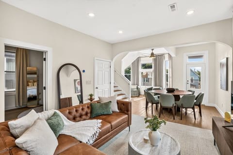 Bright living and dining area with tall windows, warm finishes, and an airy open layout.