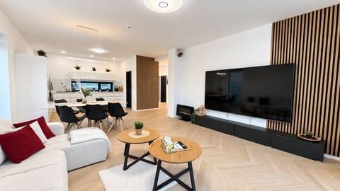 Bright open-plan living area with oversized TV and stylish dining space