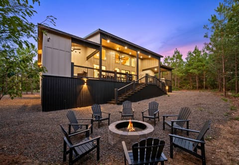 Warm exterior lighting, a spacious deck, and a cozy fire pit create an inviting place to settle in and enjoy the cabin surroundings.