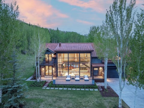 A stunning mountain retreat nestled among aspen groves and evergreens, featuring modern architecture with floor-to-ceiling windows and an expansive deck perfect for soaking in the natural beauty.