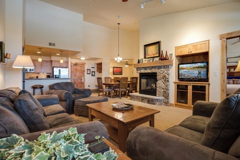 Relax in your spacious great room with plush seating, a cozy stone fireplace, and an open layout connecting the dining and kitchen areas—perfect for gatherings and unwinding after a day of adventure.