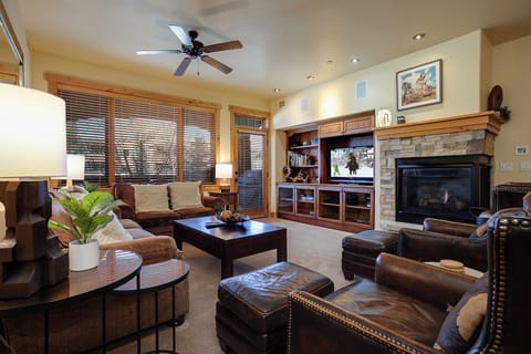Sink into luxurious leather seating by the warm stone fireplace, perfect for cozy evenings. Your home-away-from-home features elegant built-ins, natural light, and a ceiling fan to keep you comfortable year-round.