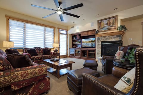 Sink into plush sofas and leather chairs in your inviting living room, where a crackling stone fireplace and entertainment center create the perfect backdrop for cozy evenings together.