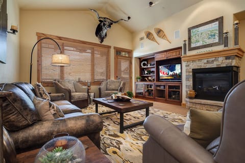 Unwind in your cozy living room, where rustic charm meets modern comfort. Sink into plush leather seating by the warm stone fireplace, perfect for evenings with loved ones.