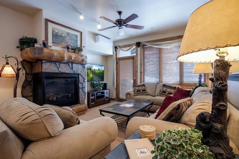 Unwind in your spacious living room featuring a cozy stone fireplace, plush seating, and rustic wood accents that create a warm, inviting mountain retreat atmosphere.