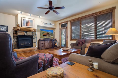 Gather around the stone fireplace in this warm, rustic living room where mountain charm meets modern comfort, perfect for cozy evenings together.