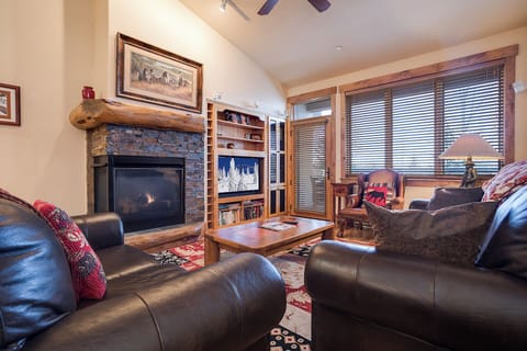 Unwind in your cozy living room with a crackling fireplace, plush leather seating, and warm rustic charm—perfect for your mountain getaway.