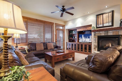 Sink into plush leather sofas and warm up by the stone fireplace in this inviting living room, where mountain getaways feel right at home.