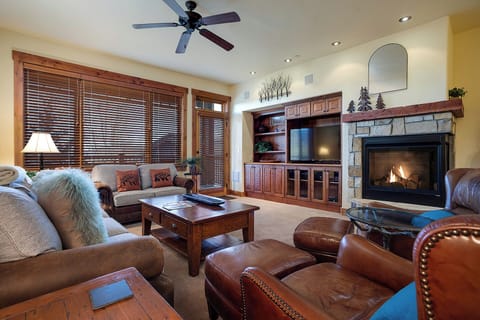 Unwind in your spacious living room with rich leather seating, a crackling stone fireplace, and mountain views through wood-framed windows—your perfect retreat after a day of adventure.