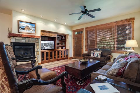 Unwind in your cozy living room with a stone fireplace, plush seating, and entertainment center. Enjoy mountain views through large windows as you relax by the fire after a day of adventure.