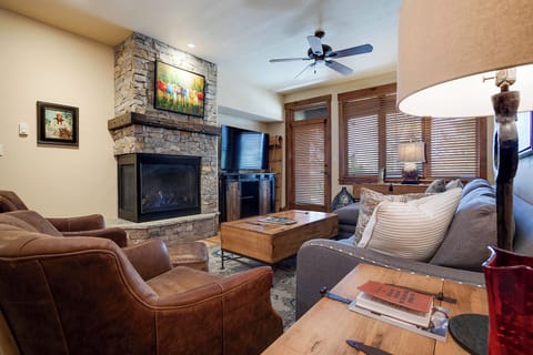 Unwind in your spacious living room with a stone fireplace, plush seating, and mountain views—perfect for cozy evenings after a day of adventure.