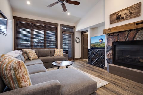Sink into the plush sectional and unwind in your cozy living room, where rustic wood tones meet modern comfort. The stone fireplace and vaulted ceiling create a warm, inviting retreat for relaxing evenings.