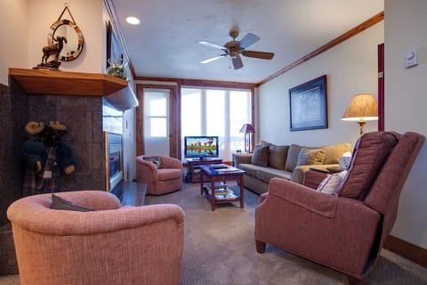 Sink into plush seating in your welcoming living room, where natural light pours through large windows and a ceiling fan keeps you comfortable. Gather around the fireplace for cozy evenings.