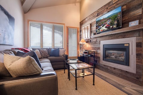 Settle into your cozy living room where rustic wood accents and a warm fireplace create the perfect retreat after a day of adventure, with entertainment ready at your fingertips.