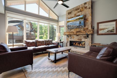 Sink into plush leather seating by the stone fireplace while soaking in natural light from soaring windows—your perfect mountain retreat awaits.