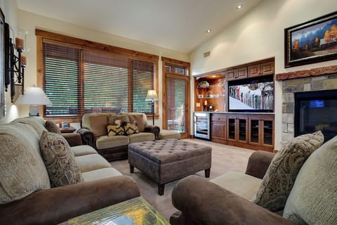 Sink into plush sofas and unwind in your spacious living room, where natural light flows through elegant wood blinds and a cozy stone fireplace awaits those cooler mountain evenings.
