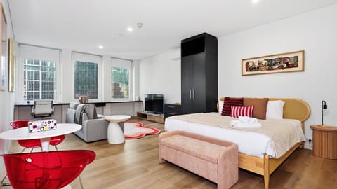 Open-plan studio layout featuring a cozy bed, seating area, and desk space.