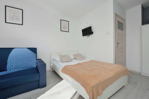 Bright bedroom with a double bed, a blue sofa, and minimalist wall decorations.