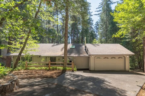 A charming woodland retreat nestled among towering pines, offering a peaceful escape in a serene forest setting with spacious parking and a welcoming front porch.