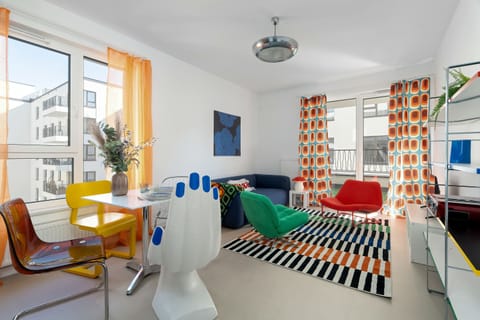 Modern living room has colorful furniture, large windows, and bright decorative details.