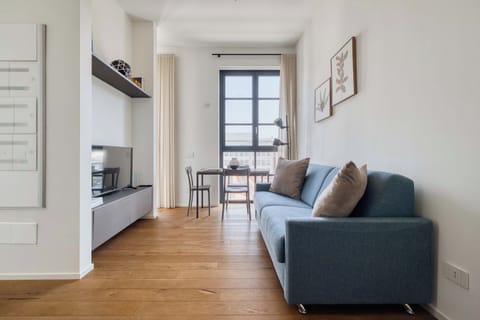 Relax in the cozy living room, featuring comfortable seating and a TV, perfect for unwinding after a day exploring Milan.