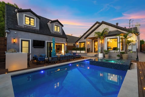Home features a saltwater pool, firepit, outdoor kitchen, BBQ grill, and covered patio with outdoor furniture, surrounded by Ipe wood decking and mahogany fencing.
