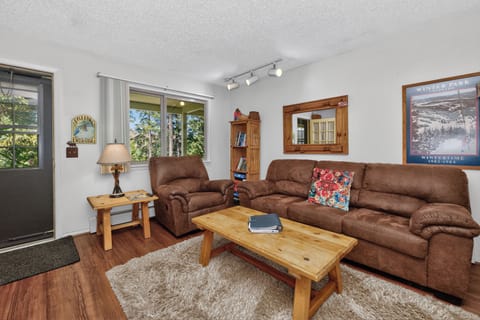 Sink into the plush brown sofas and enjoy the natural light streaming through the windows. This cozy living room blends rustic wood accents with comfortable seating, perfect for unwinding after your adventures.