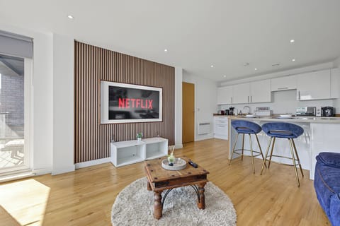 Bright open-plan lounge with sleek kitchen, breakfast bar & wall-mounted TV