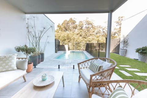Covered poolside patio with stylish lounge seating and private garden views