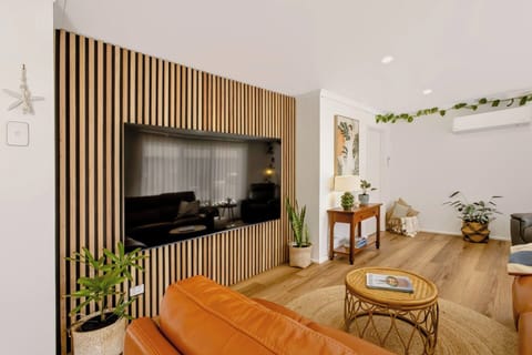 Bright modern lounge with feature wall, large TV, and warm natural styling