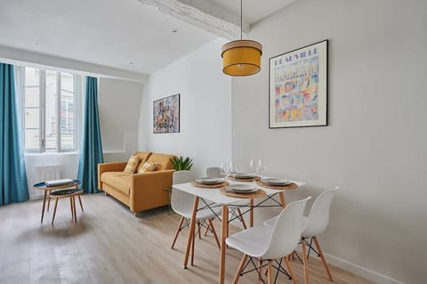 Salon avec canapé lit, cuisine ouverte, espace repas et smart TV