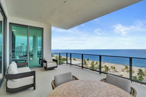 Wide wraparound balcony with outdoor seating and unobstructed ocean and beach views straight ahead.
