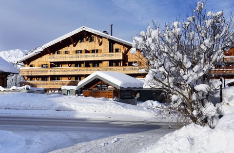 Wooden building and snow-laden tree in snowy landscape