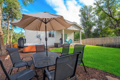 Welcome to Golden Grove! Chairs pull up to a table beneath a wide canvas umbrella, with the grill and the hot tub a few steps away along the house. Long outdoor meals run easy here, with the lawn opening up just beyond the covered patio.