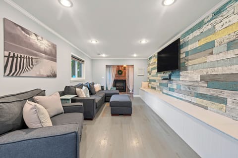 Bright coastal-inspired living room with fireplace, large TV, and plenty of seating