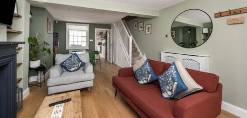 A calm yet characterful room with layered Farrow & Ball green tones, mixing deep and soft shades for depth and warmth. Pale wooden floors balance the darker walls, while a deep burnt orange Swfyt sofabed s the space with a refined, contemporary feel.