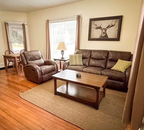 Living room with a dining room table and flat screen Tv mounted on the wall. 