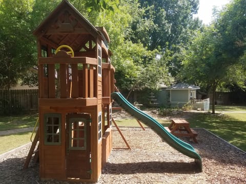 Private playground in backyard with swings, slide, clubhouse and picnic table