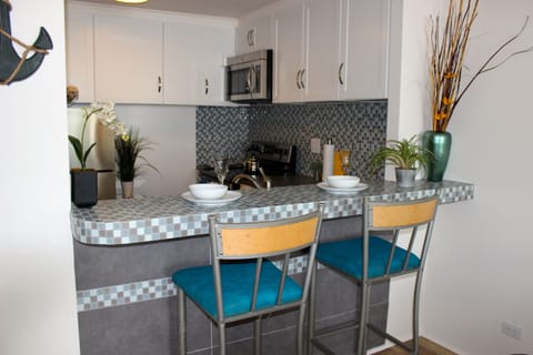 A bar-top with two bar stools to match, a fully-stocked kitchen